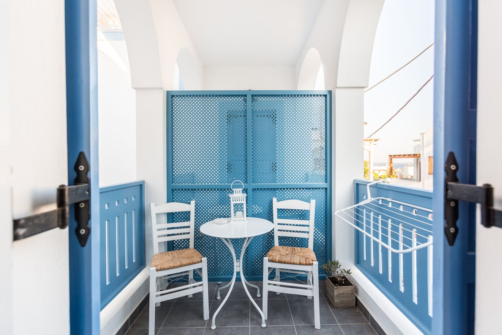 Private balcony with blue lattice screen, bistro table and rush-seat chairs