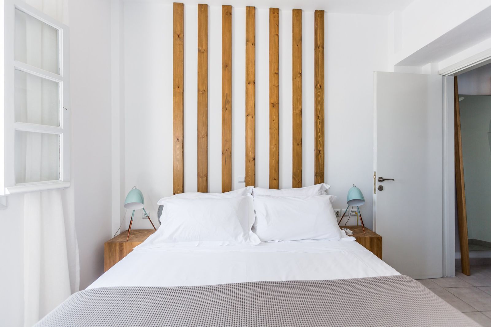 Double bed framed by oak slats and bedside lamps