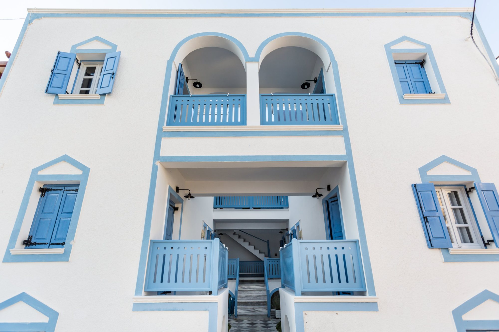 Front of Fanouris Condo in Kamari, Santorini: white walls, blue shutters, twin arched balconies and the entrance to the courtyard